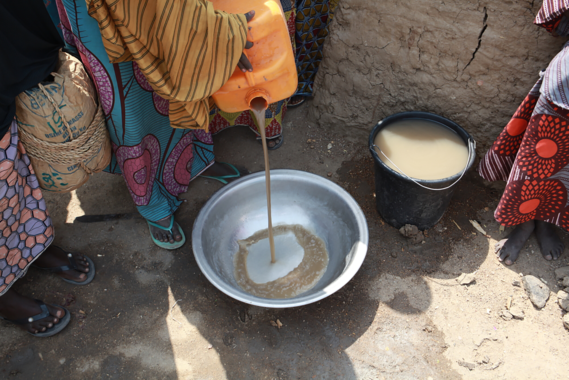 A woman pours out dirty water that has been scooped up from spillage at the borehole. This is the water people have to wash themselves and their clothes with. © Scott Hamilton/MSF