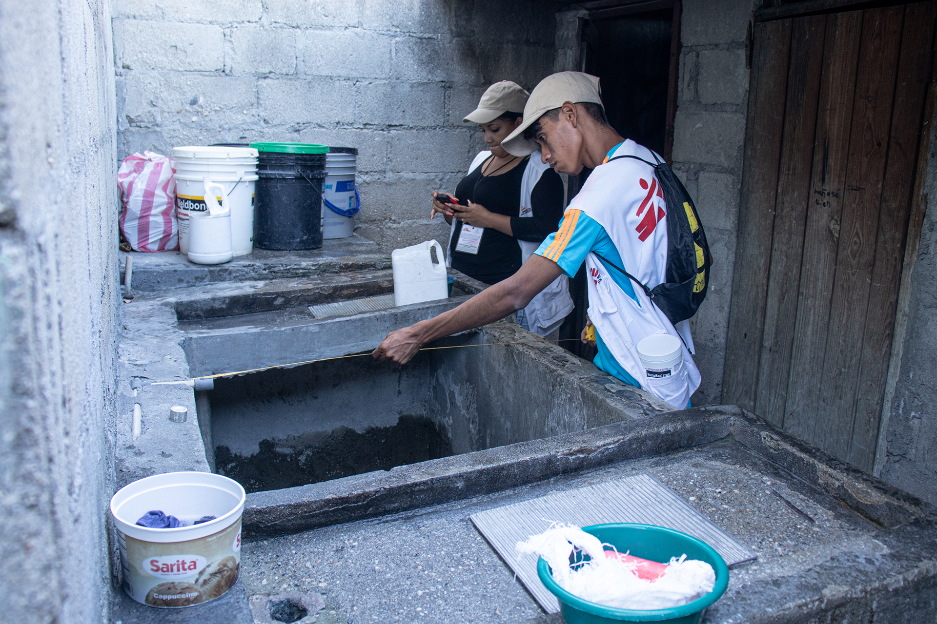Health promoters measure a water tank so they can apply the exact amount of larvicide necessary for it to be effective. © Arlette Blanco/MSF 