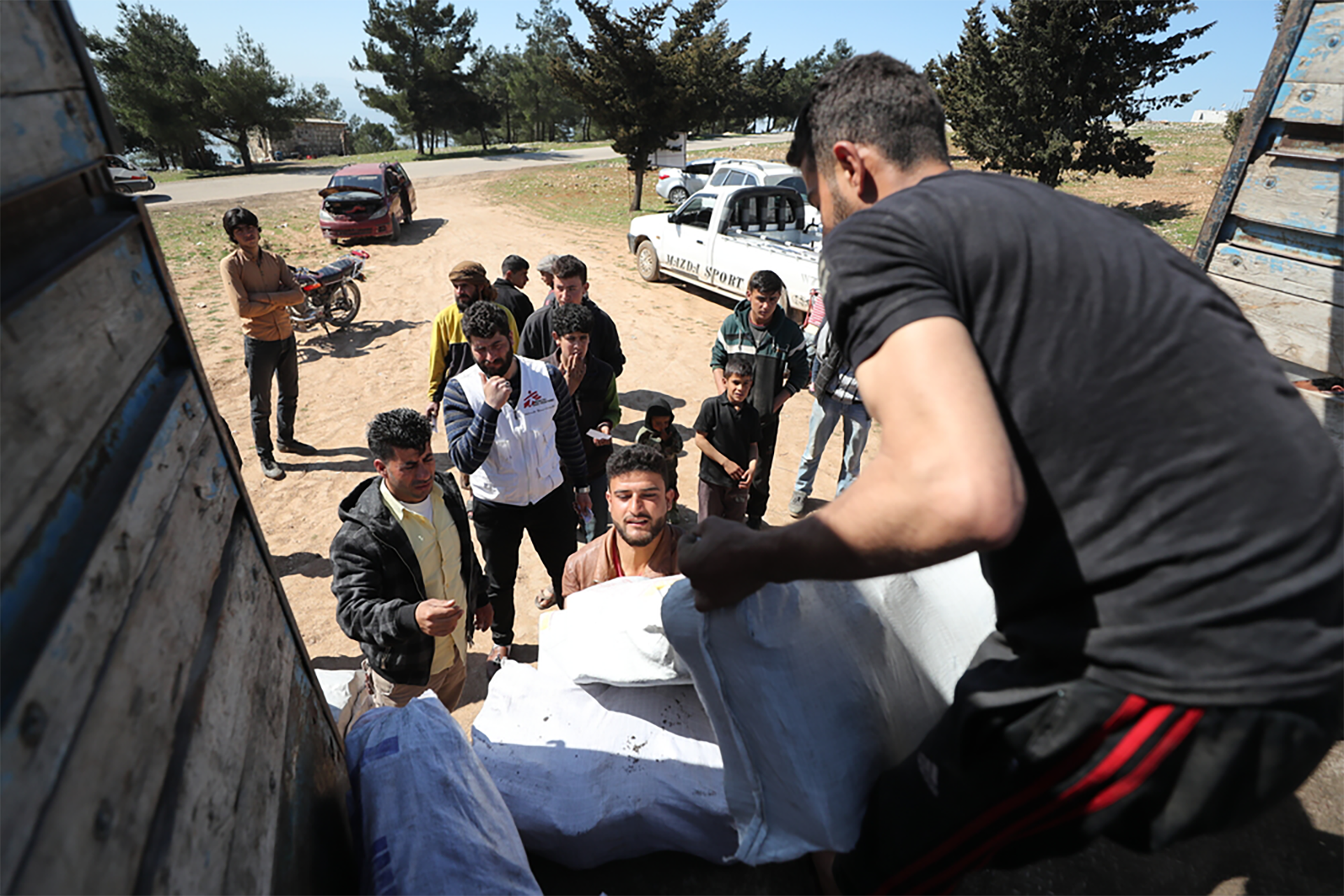 In Mar 2020, an MSF team distributed heating material in a camp for internally displaced people in northwest Syria. An MSF team is unloading the truck as people line up to receive their donations. © MSF